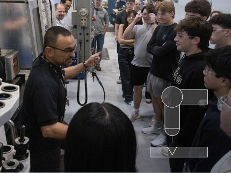While Pat Napolitano, UTRS Vice President, Prototype Manufacturing looks on, Branch Chief Frank Petrosillo describes manufacturing processes and explains equipment used to prototype armament hardware. (U.S. Army photo by Todd Mozes). Advanced Manufacturing icon overlaid in bottom right of image.