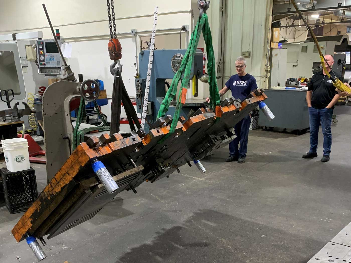 Setting one of the 4-ft wide by 8-ft long by 2-inches thick progress die set plates in place. Each piece weighs about 3,000 pounds.